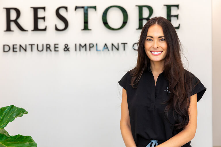 Dr. Mencini smiling in front of her practice logo